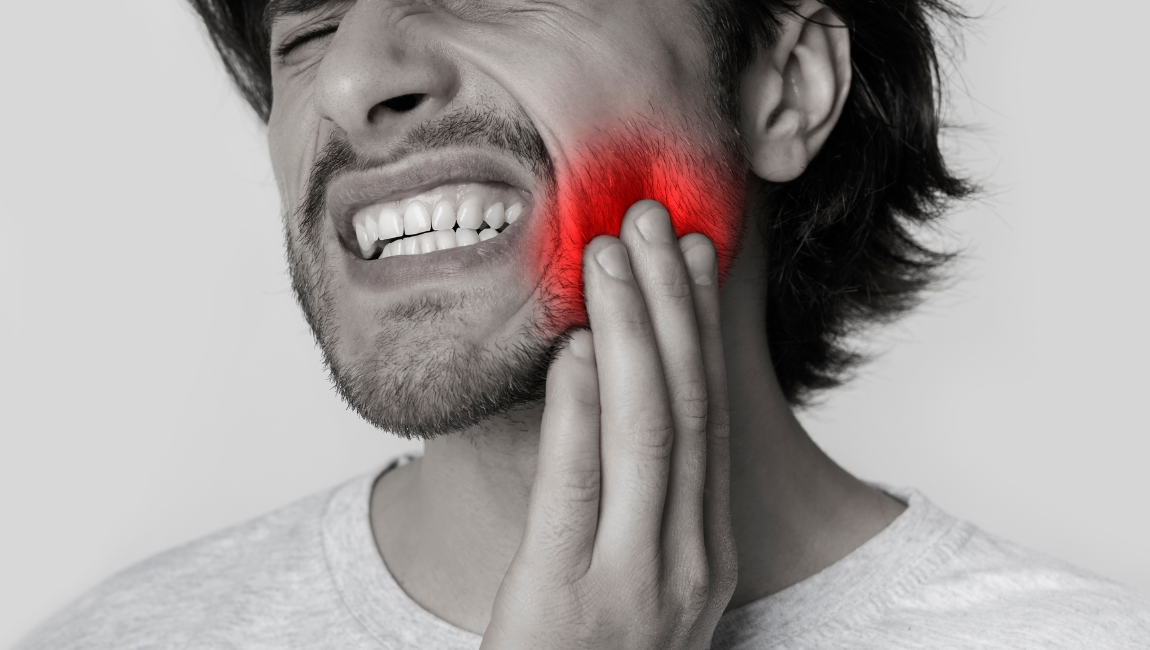 Man holding his jaw in pain experiencing a dental emergency in Costa Mesa