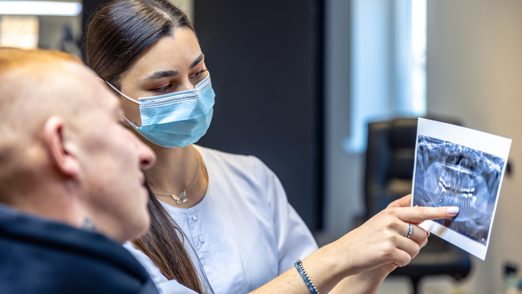 Dentist reviewing a patient's X-ray to plan a tooth extraction at our Costa Mesa office